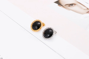 Detail view of oval black crystal studs with gold and silver stainless steel frames