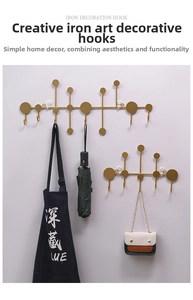Detail of gold geometric metal hooks holding an apron and bags on a wall