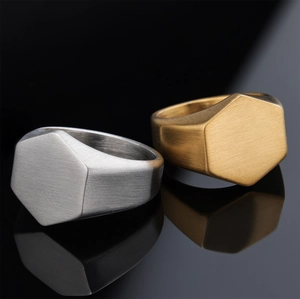 Macro view of silver and gold hexagonal signet rings with brushed metal texture