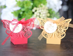 Detail of laser-cut butterfly gift boxes in red and gold with silk ribbons and tags