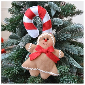 Close-up of felt gingerbread man and candy cane hanging on a green Christmas tree branch