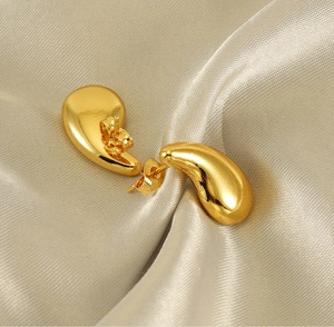 Detailed macro shot of 18K gold plated teardrop earrings on elegant satin fabric