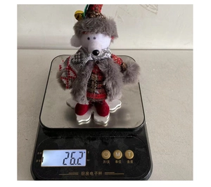 Detailed view showing the plush Christmas gnome weight of 26.2 grams on a kitchen scale