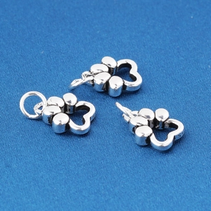 Three S925 sterling silver hollow flower charms on blue textured fabric background