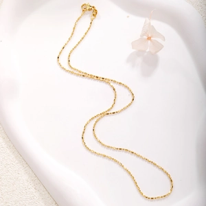 Close-up of gold plated thin ball chain necklace with a lobster clasp on white tray