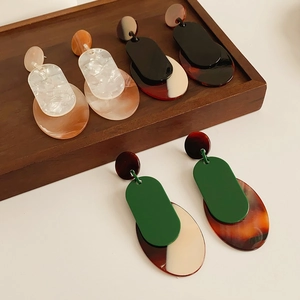 Detailed shot of three pairs of vintage geometric acrylic earrings on a wooden tray