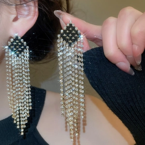 Macro detail of long diamond tassel earrings featuring black and white rhinestone accents