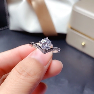 Close-up of a sparkling 1 carat diamond ring held by hand, showing V-shaped detail.