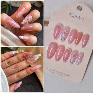 Detail of pink zebra stripe press-on nails with 3D floral accents and water droplets
