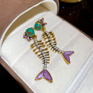 Detail of fish bone drop earrings with green enamel and pearl accents in a gift box