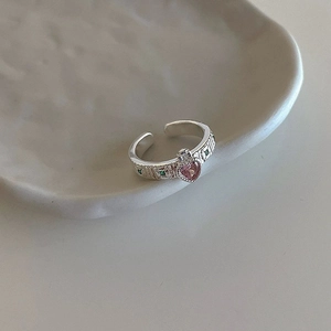 Detail of vintage silver open ring with pink heart stone and green zircon accents