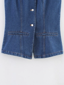 Gros plan d'un gilet en jean bleu foncé avec boutons argentés et coutures contrastées