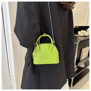 Macro view of fluorescent green shell bag with lychee grain leather and silver bead chain