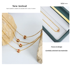 Detail of a gold cubic pendant featuring vibrant red hearts on a delicate chain necklace