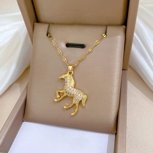 Close-up of a gold horse pendant necklace with crystal pave on a leather jewelry box