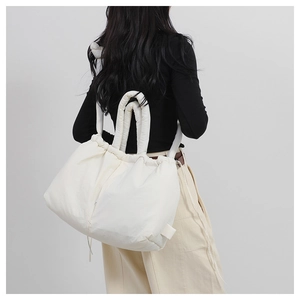 Detailed back view of a white quilted nylon tote bag with drawstring on a female model