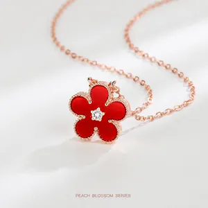 Detail of rose gold five-petal flower necklace with red agate and sparkling center crystal