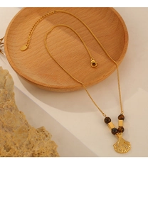 Detail of vintage gold necklace with shell pendant and tiger eye beads on wood tray