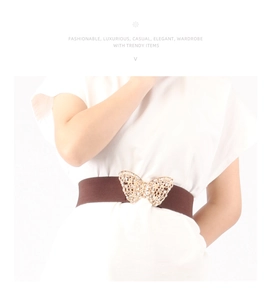 Detail of a brown elastic belt featuring a gold butterfly buckle with sparkling rhinestones
