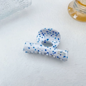 Detail of white acetate hair claw with blue marble dots and gold Amy Bear text