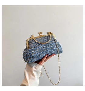 Close-up of blue tweed chain bag with gold metal frame and woven texture detail
