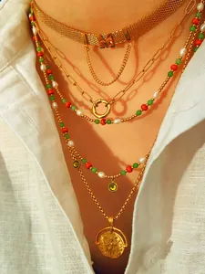 Detail of layered gold chains with colorful beads and vintage coin pendant on white fabric