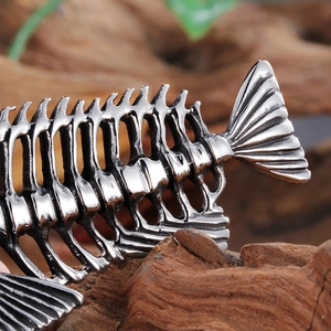 Detailed close-up of a silver fishbone pendant showing intricate metallic texture and craft