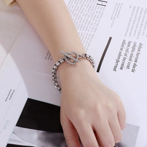 Detail view of silver metal chain bracelet featuring a unique heart-shaped toggle clasp