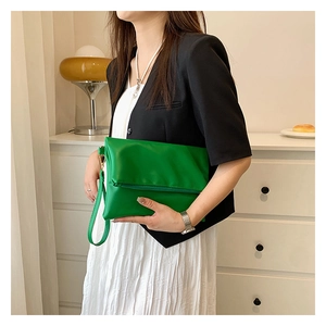 Detalle de bolso de mano sobre verde brillante en cuero PU suave con correa