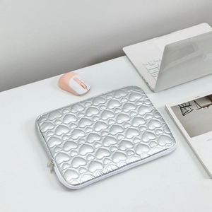 Detail of silver heart quilted laptop sleeve with white zipper on a modern office desk