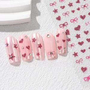 Detail of pink glitter heart and bow nail stickers applied on manicured nails
