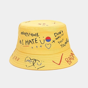 Détail du chapeau bob en toile jaune avec imprimés graffiti et lettrage style urbain