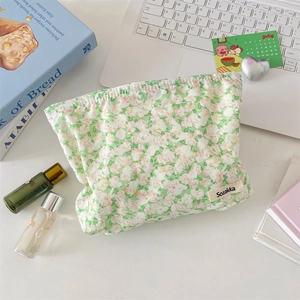 Flat lay of small floral cotton makeup bag with brand label and lifestyle props