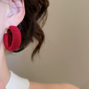 Gros plan de créoles rouges en forme de C floquées avec finition velours sur un mannequin