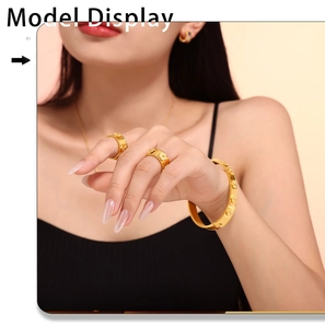 Dettaglio di bracciale e anelli in oro 18k con rilievo floreale e bordo perlato su modella