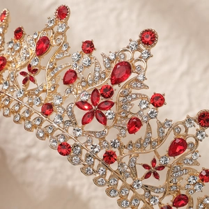 Detail shot of golden bridal crown featuring red teardrop gems and floral crystal patterns