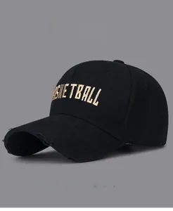 Detail of gold basketball embroidery and distressed holes on black cotton baseball cap