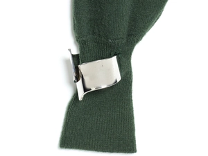 Détail d'un large bracelet géométrique en métal argenté sur une manche en maille vert foncé