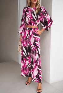Full body shot of a woman in pink and black abstract print two-piece set with wide leg pants