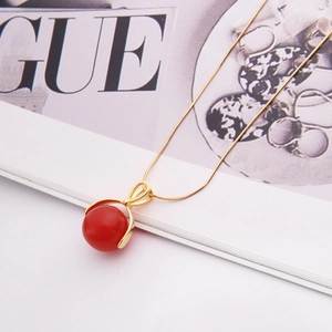 Élégant collier en or avec un pendentif sphérique rouge sur un magazine de mode chic