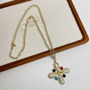Detail of vintage gold cross necklace with baroque pearls and colorful gemstones