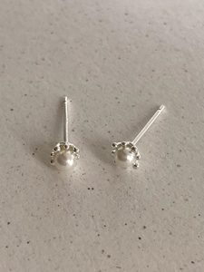 Close-up of minimalist 925 silver stud earrings with white pearls and beaded edges