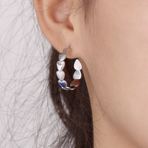 Close-up of heart-shaped chain hoop earrings in silver finish on model ear