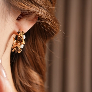 Detailed view of vintage gold flower earrings with white pearls and brown tiger eye stones