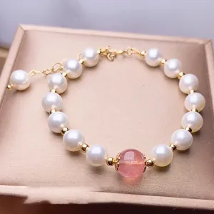 Detail of strawberry crystal and pearl bracelet with golden chain on silk box