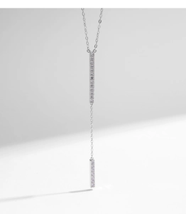 Close-up of silver Y-shaped necklace with shimmering zircon-studded bar pendants