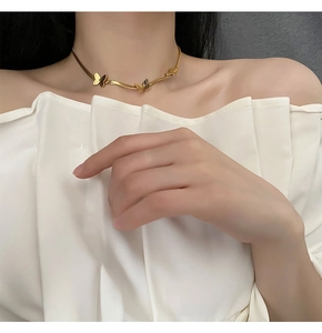 Gros plan du collier choker papillon doré sur modèle montrant les détails fins