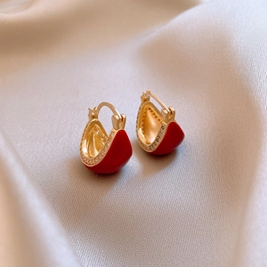 Close-up of golden tiger eye hoop earrings with small crystals on soft silk fabric