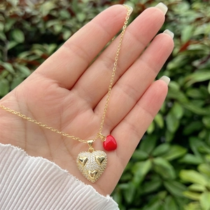 Detail of 18K gold-plated double heart pendant necklace with white zircons and red heart
