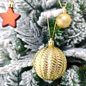 Gros plan d'une boule de Noël dorée texturée suspendue à une branche de sapin festive